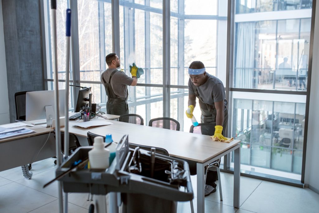 Professional cleaners sanitizing office desks and windows during a commercial cleaning session in Perth